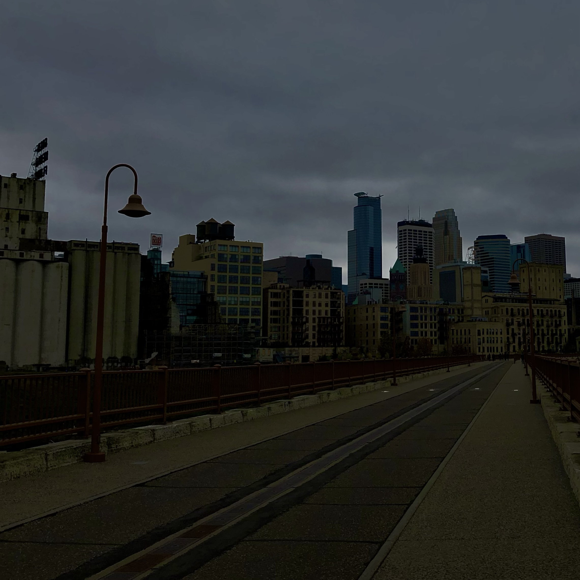 Photo of the Minneapolis skyline from Stone Arch Bridge with gray skies overhead.